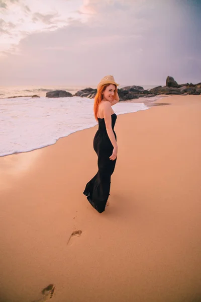 Junge Frau geht bei Sonnenuntergang am Strand entlang, Rückansicht — Stockfoto