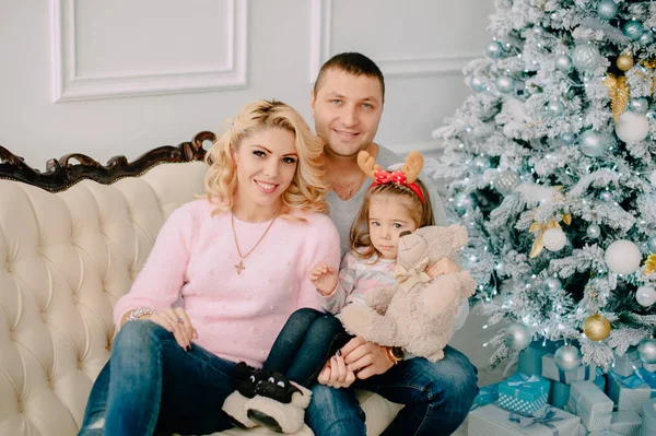 Familia joven sentada en un sofá cerca del árbol de Navidad —  Fotos de Stock