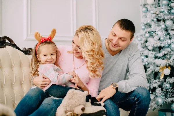 Familia joven sentada en un sofá cerca del árbol de Navidad —  Fotos de Stock