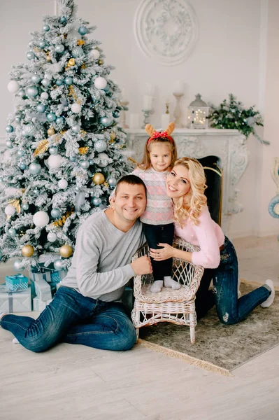 Padres jóvenes jugando con el bebé cerca del árbol de Navidad —  Fotos de Stock