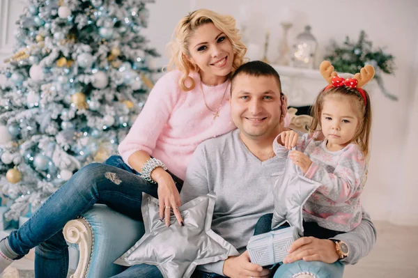 Junge Familie auf dem Hintergrund des Weihnachtsbaums — Stockfoto