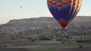 bir grup insan balonunda kayaların üzerinden uçan