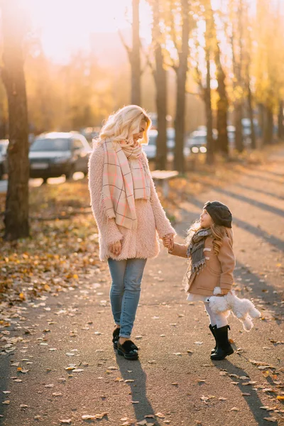 mother and daughter walking in autumn city