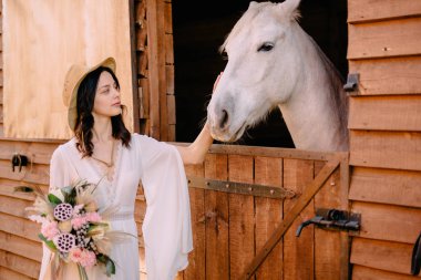 Genç boho stil gelin beyaz at okşayarak