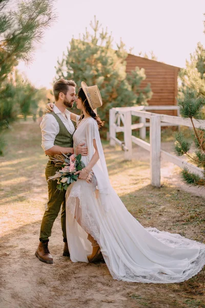 Boho-style newlyweds walk on ranch, summer day — Stock Photo, Image