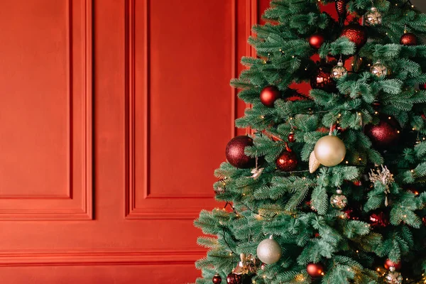 Árbol de Navidad decorado cerca de la pared roja, de cerca — Foto de Stock