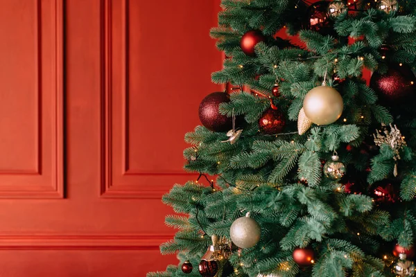 Árbol de Navidad decorado cerca de la pared roja, de cerca — Foto de Stock