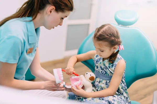 Dentista pediátrico ensina menina a escovar os dentes — Fotografia de Stock