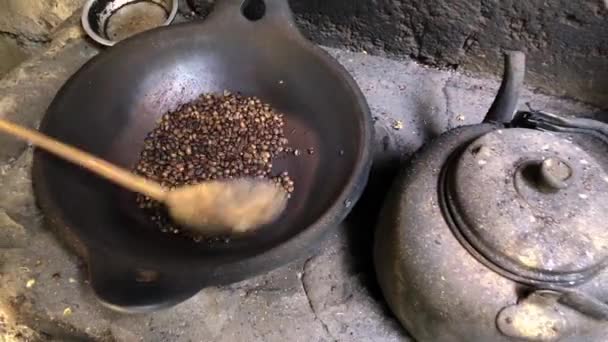 Женщина жарит кофейные зерна в старой сковородке — стоковое видео