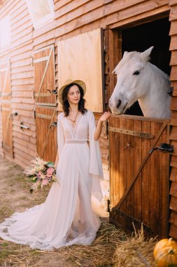 Genç boho stil gelin beyaz at okşayarak