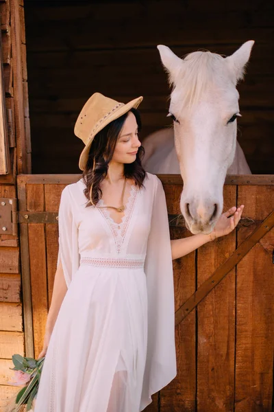 Genç boho stil gelin beyaz at okşayarak — Stok fotoğraf
