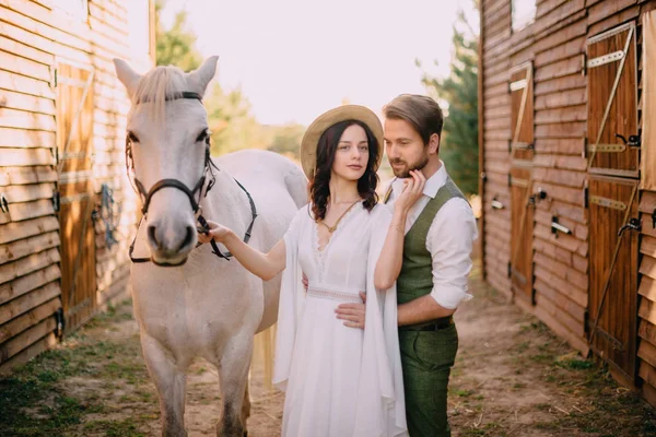 Coppia elegante in piedi e abbracciando vicino scuderie — Foto Stock