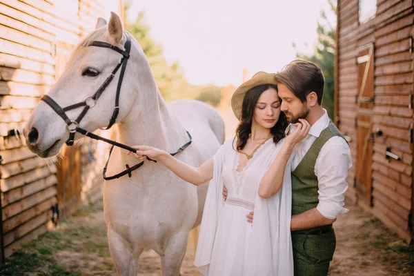 Pareja elegante de pie y abrazos cerca de establos —  Fotos de Stock