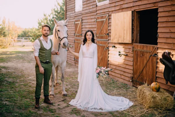 Jeunes mariés de style boho debout près du cheval sur le ranch — Photo