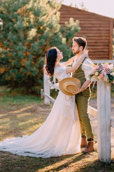 Newlyweds in cowboy style standing and hugging on ranch