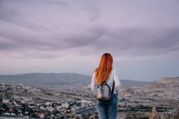 young woman tourist stands against mountain landscape