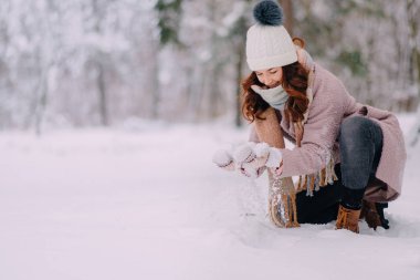 parkta eller genç kadın kartopu yapma