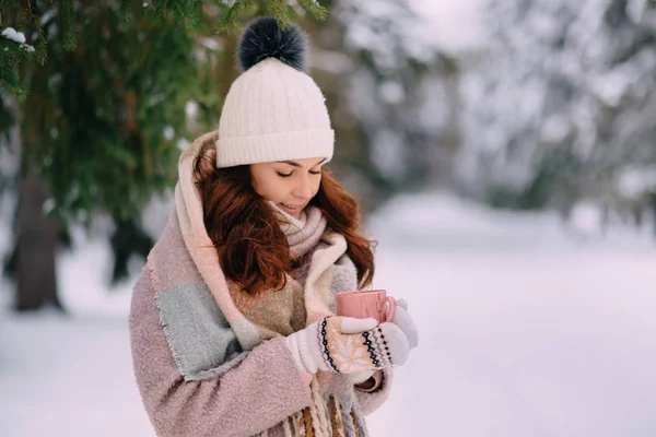 young female holding cup of hot drink in winter park