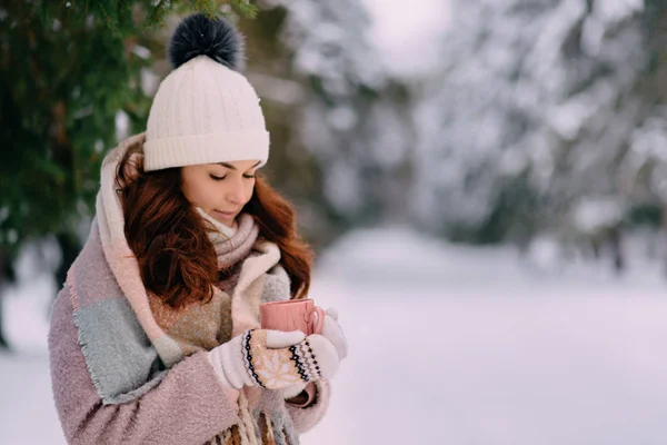 Joven hembra sosteniendo taza de bebida caliente en el parque de invierno —  Fotos de Stock