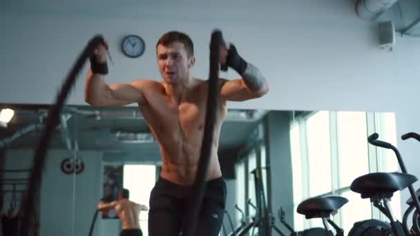 Hombre fuerte haciendo ejercicio con cuerdas de batalla en el gimnasio — Vídeos de Stock