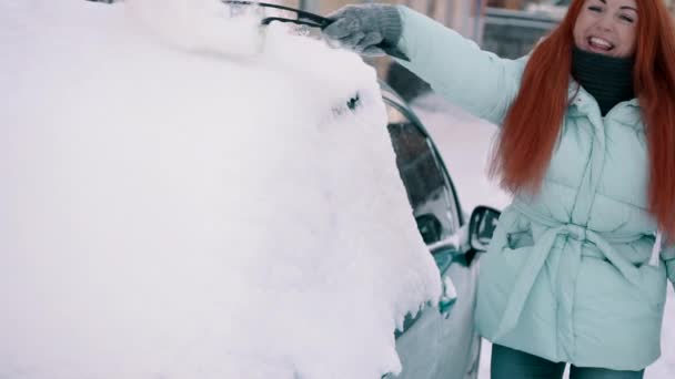 Mujer alegre limpia la nieve de su coche — Vídeo de stock