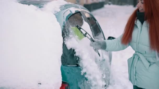 Mujer alegre limpia la nieve de su coche — Vídeos de Stock