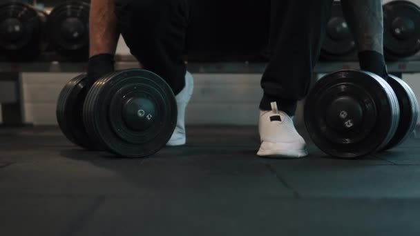 Uomo raccoglie manubri dal pavimento per l'esercizio in palestra — Video Stock