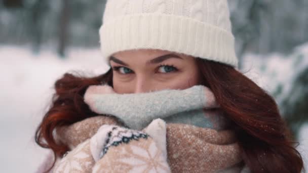 Жінка вкриває обличчя від холоду в сніжному лісі — стокове відео