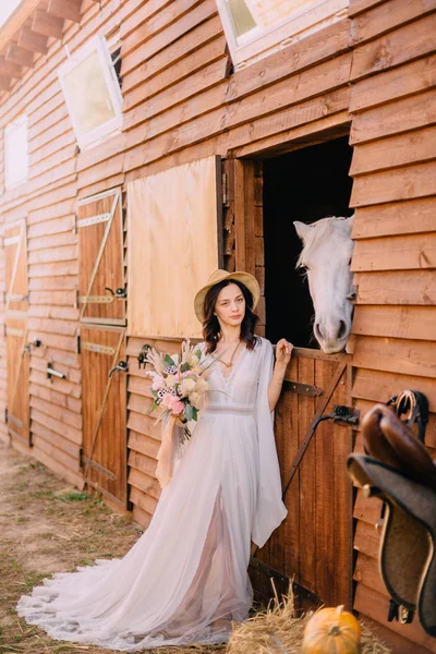 Joven boho estilo novia es acariciando caballo blanco — Foto de Stock