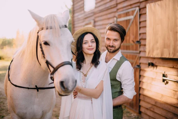 Élégants jeunes mariés se tiennent près du cheval et regardent dans la caméra — Photo