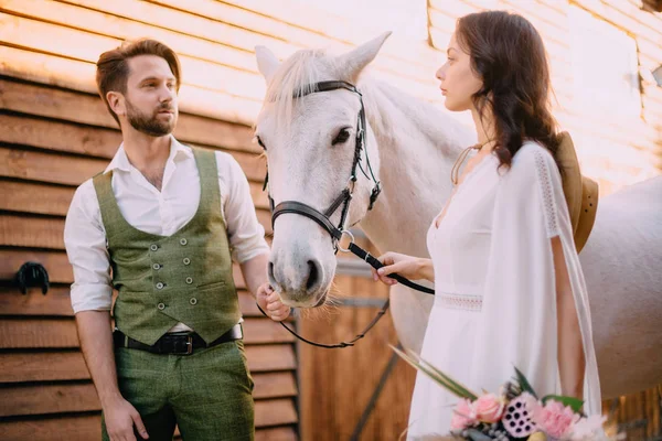 Sposi si guardano l'un l'altro tenendo il cavallo — Foto Stock