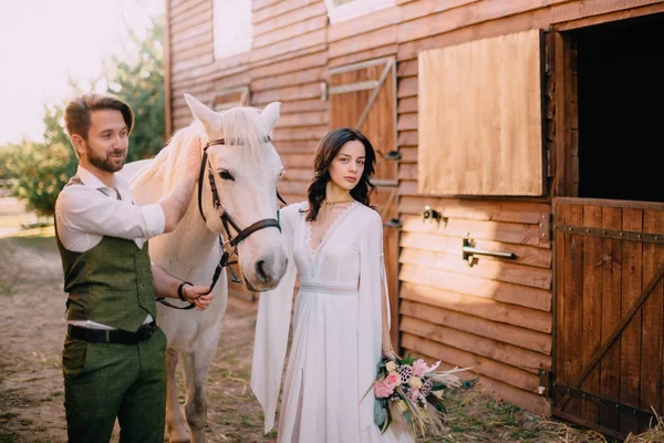 Jeunes mariés de style boho debout près du cheval sur le ranch — Photo