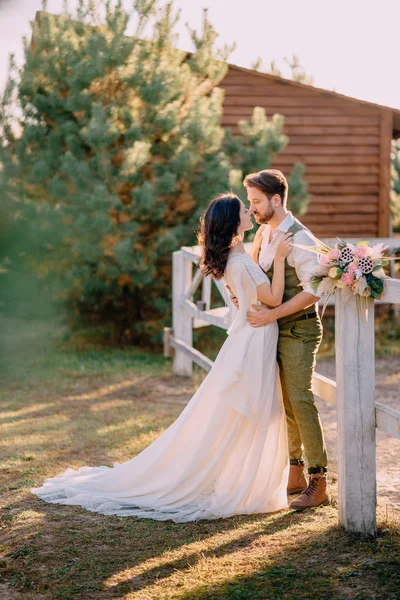 Jeunes mariés dans le style cow-boy debout et câlins sur le ranch — Photo