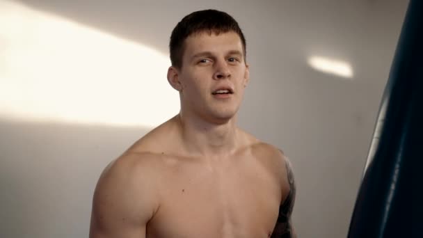 Portrét mladého boxera s tetováním poblíž boxovací pytel — Stock video