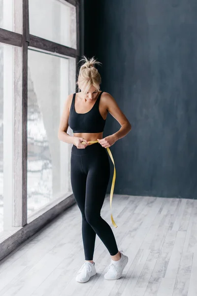 Slim woman measuring waist with tape measure in centimeters — Stock Photo, Image