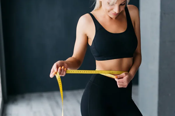 Athletic slim woman measuring her waist by measure tape — Stock Photo, Image