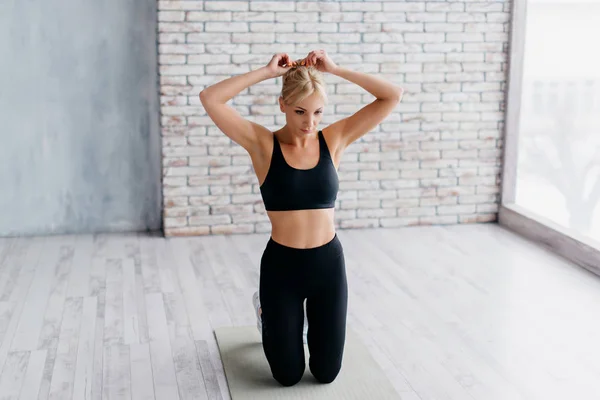 Sportos nő ül szőnyegen fitnesz stúdió — Stock Fotó