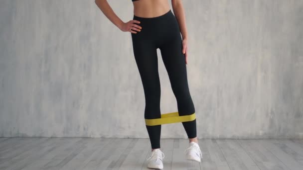 Mujer fitness haciendo ejercicios de piernas con goma de fitness amarilla — Vídeos de Stock