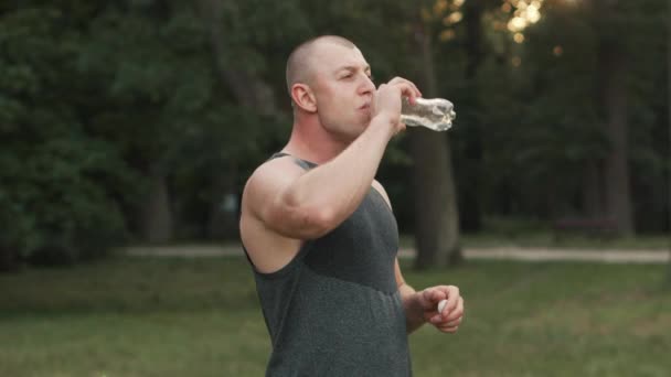 Sports couple drinking water after workout in park — Stock Video