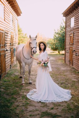 Genç boho stil gelin beyaz at okşayarak