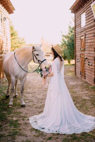 Giovane boho stile sposa è accarezzando cavallo bianco — Foto Stock