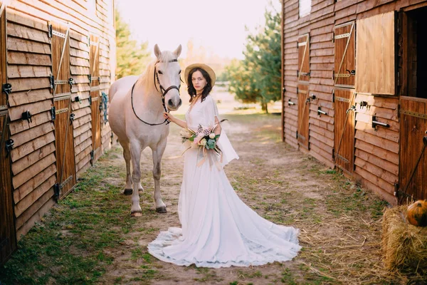 Young boho style bride is stroking white horse — Stock Photo, Image