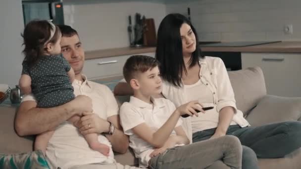 Familia feliz viendo la televisión en casa en el sofá — Vídeos de Stock