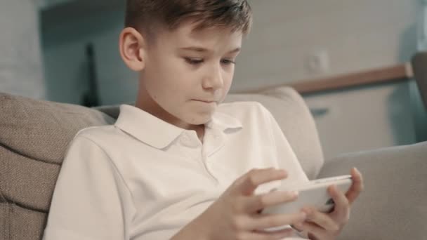 Boy uses smartphone while sitting on couch, close-up — Stock Video