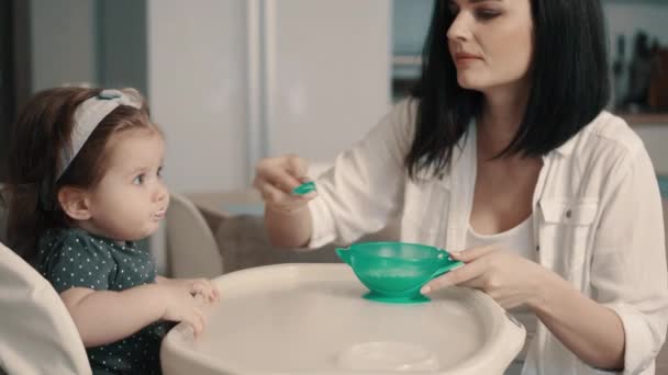 Ung mamma matar lilla dotter med sked — Stockvideo