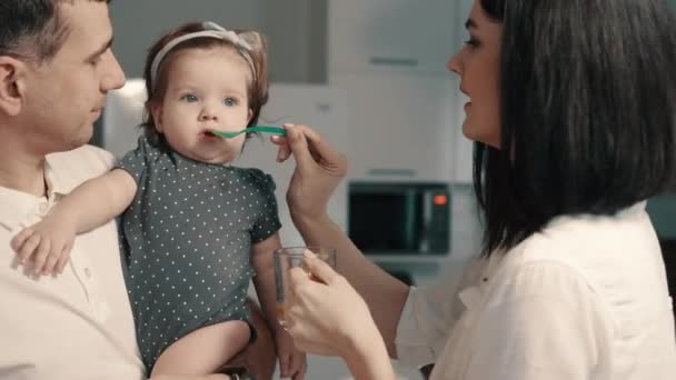 Jovens pais alimentam a filha do bebê em casa — Vídeo de Stock