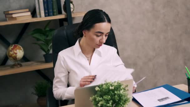 Mujer joven está mirando el papeleo en su escritorio en la oficina — Vídeos de Stock