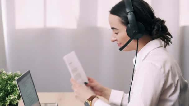 Female call center worker answers customer call in office — Stock Video