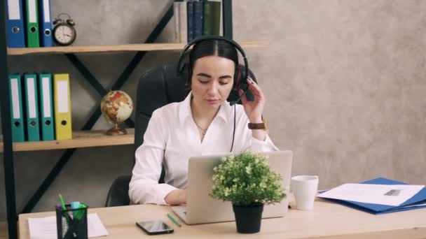 Сотрудница колл-центра отвечает на звонки клиентов в офисе — стоковое видео
