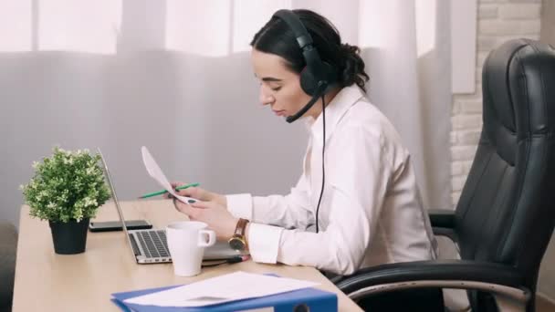 Female call center worker answers customer call in office — Stock Video